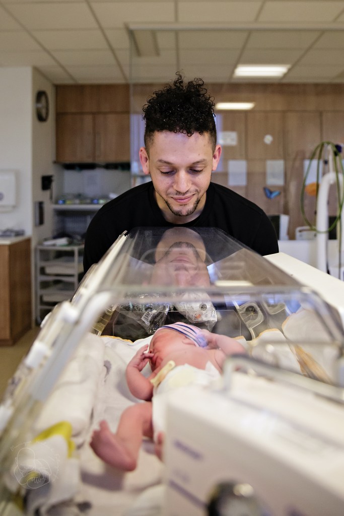 Trotse papa kijkt naar zijn baby in de couveuse