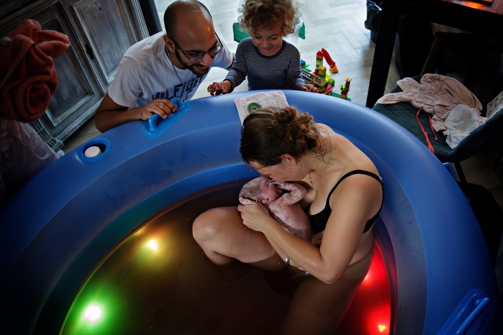 grote zus ziet haar babybroertje geboren worden, thuisbevalling in bad